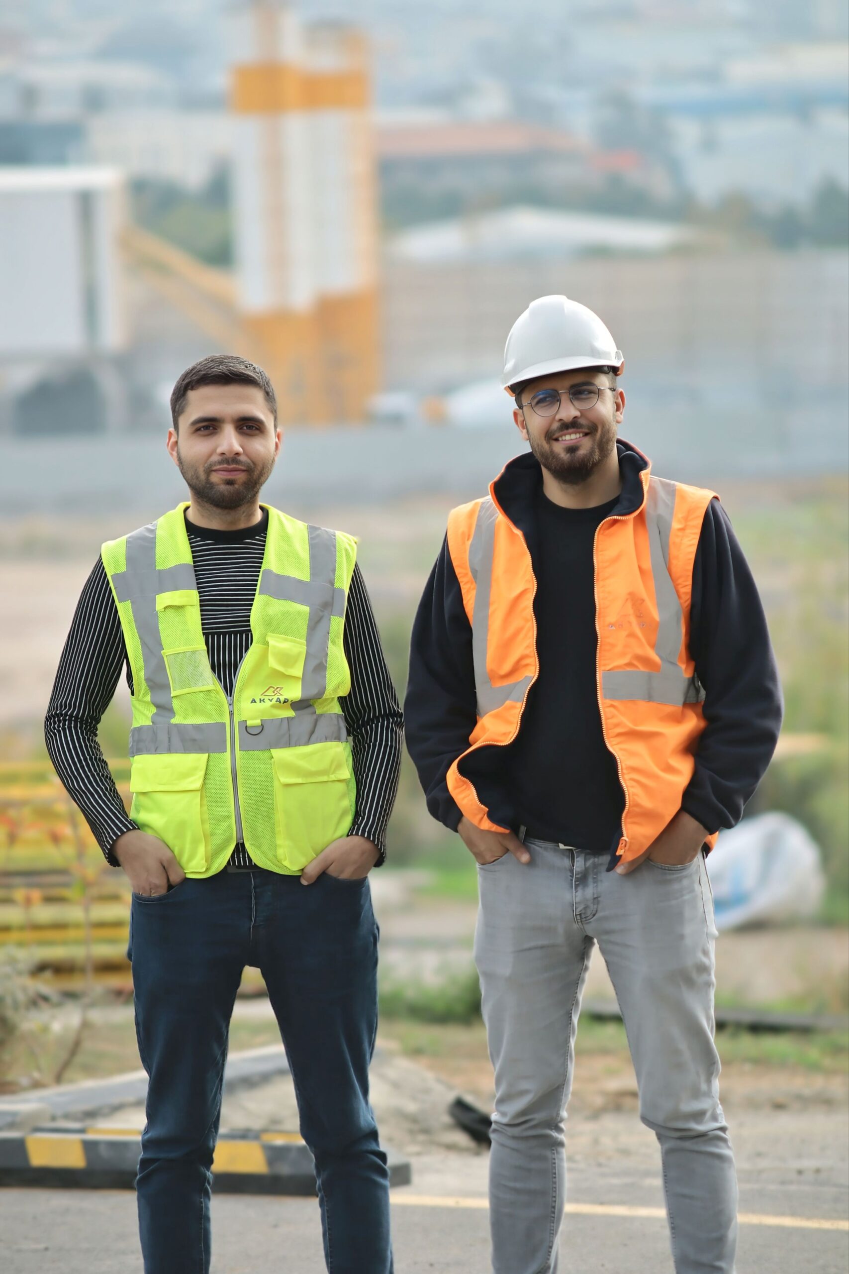 Two construction workers in safety gear at an outdoor site, showcasing teamwork.