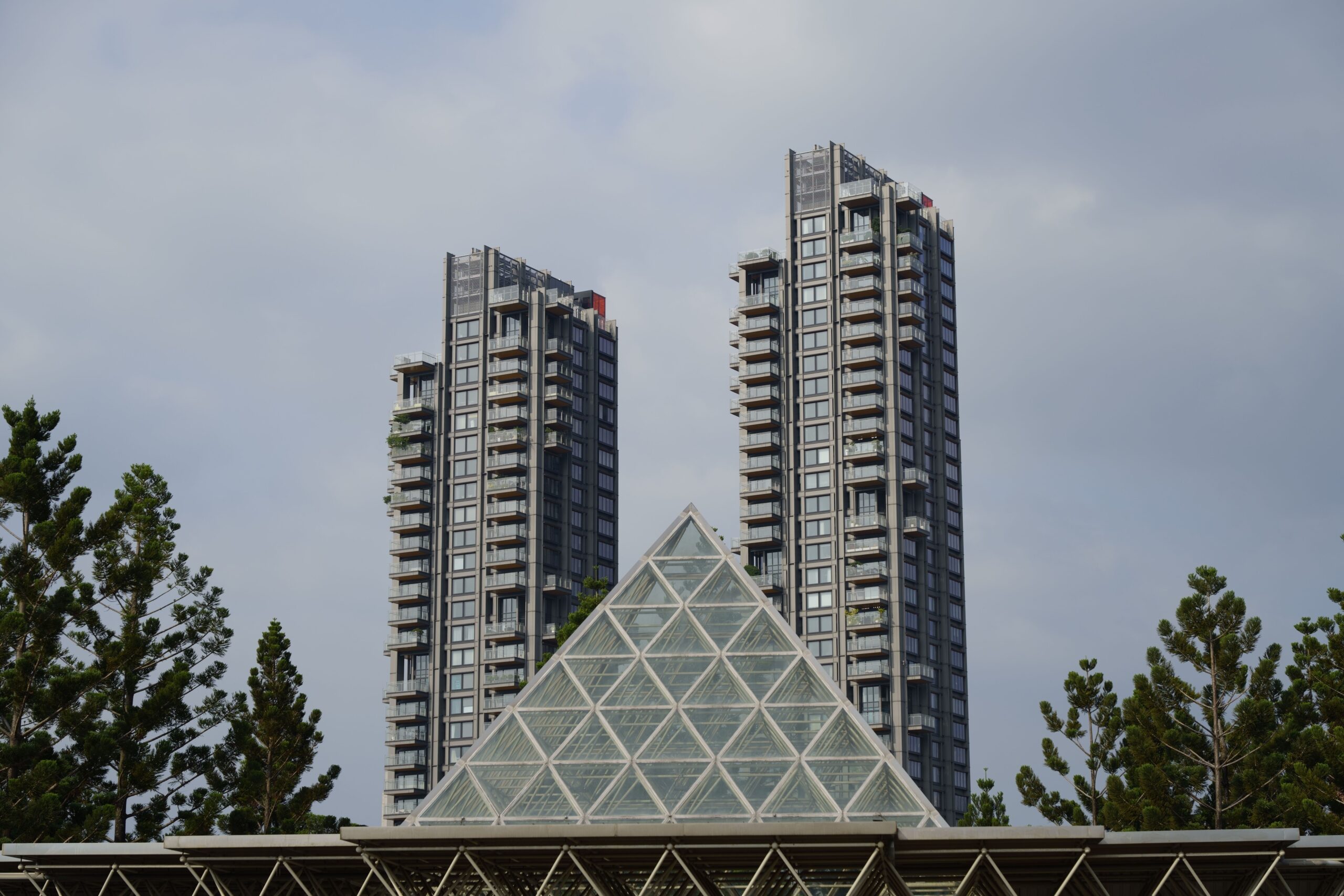 Modern skyscrapers and glass pyramid structure surrounded by greenery in Taipei, Taiwan.